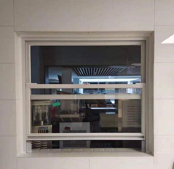 Moderne, enkelvoudig hangende, verticale schuiframen voor de keuken met zwart aluminium frame en roestvrijstalen ophangsysteem.